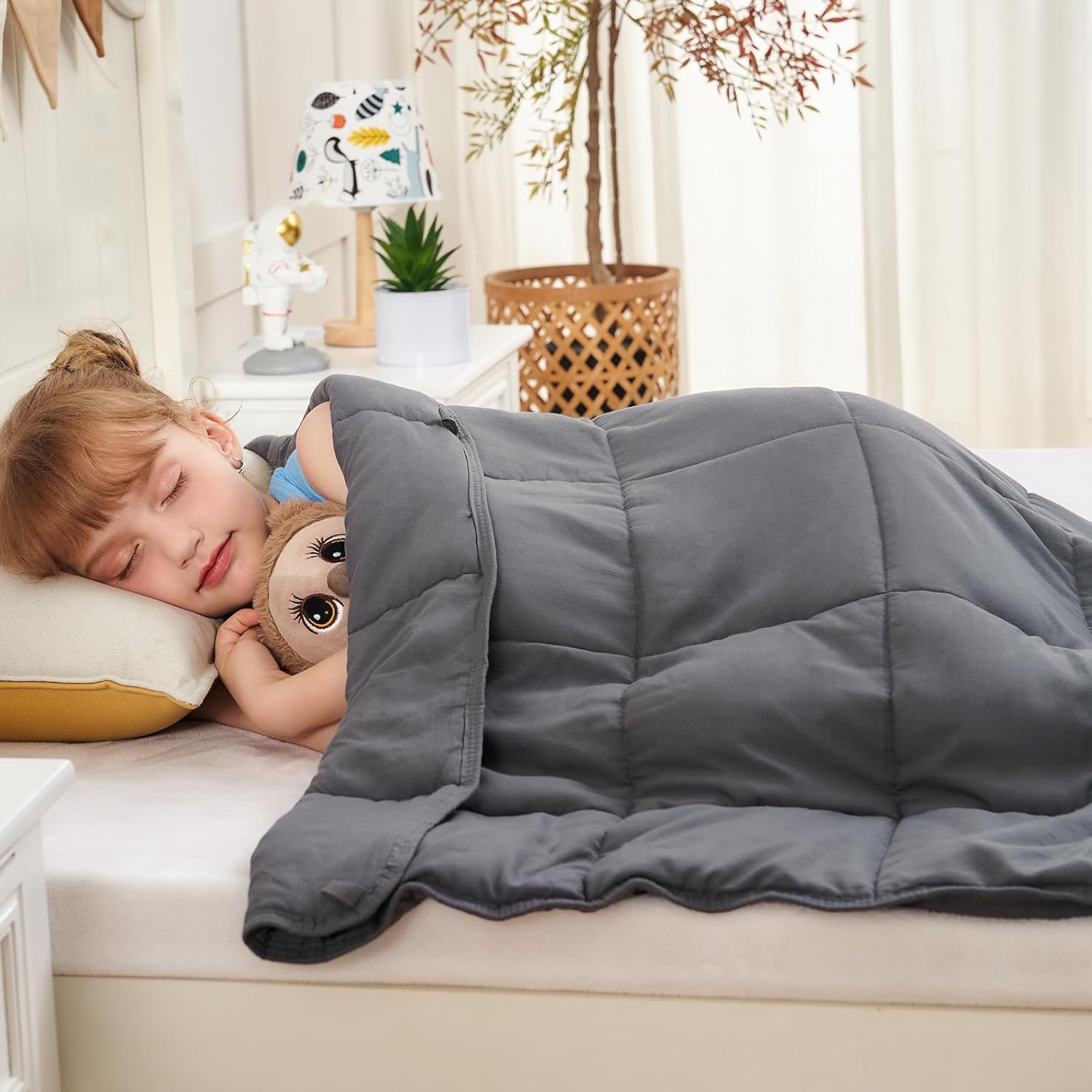 child sleeping in bed side facing with Weighted Blanket in use from AskSAMIE